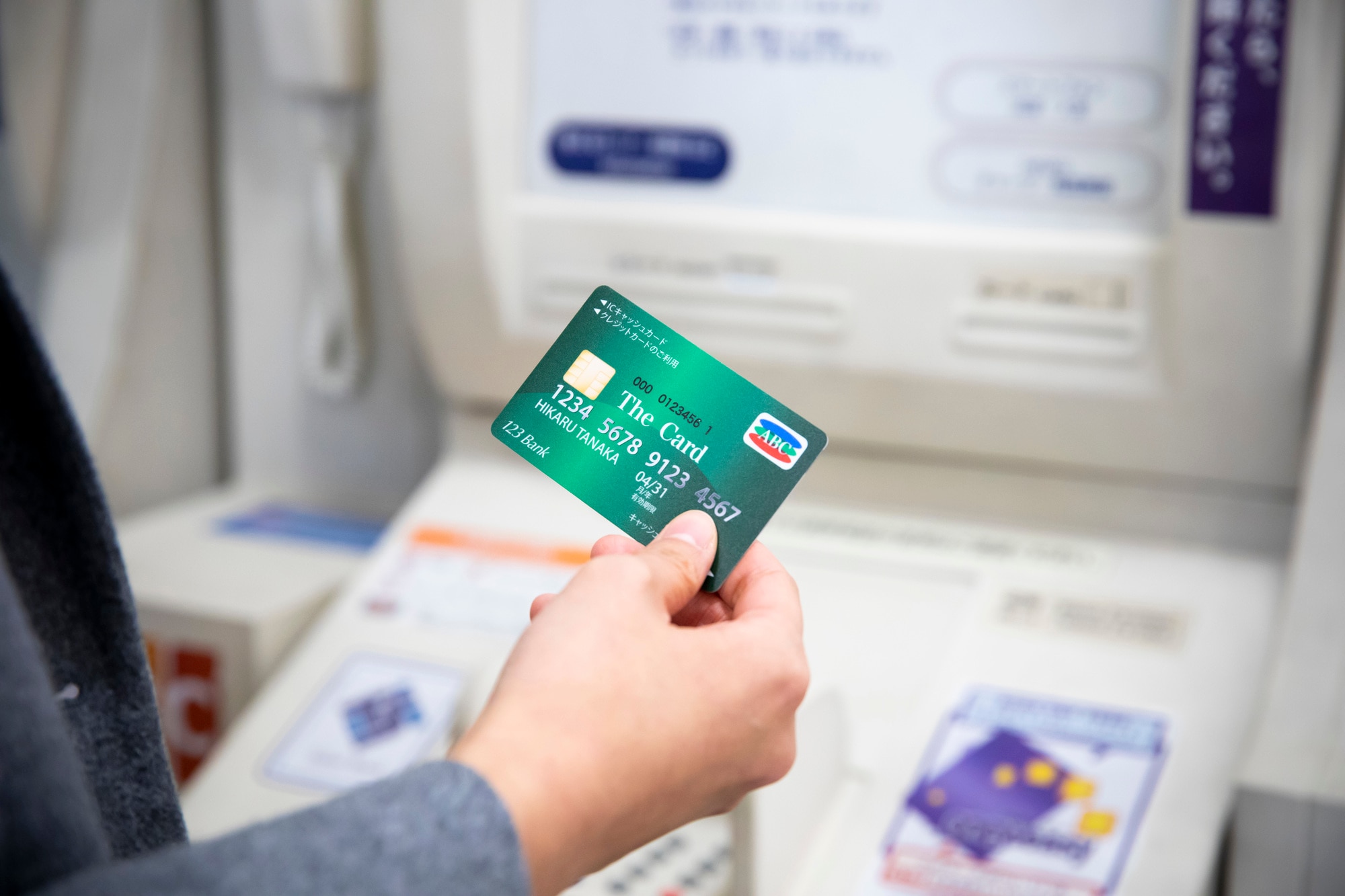 ATMの前でカードを持つ男性