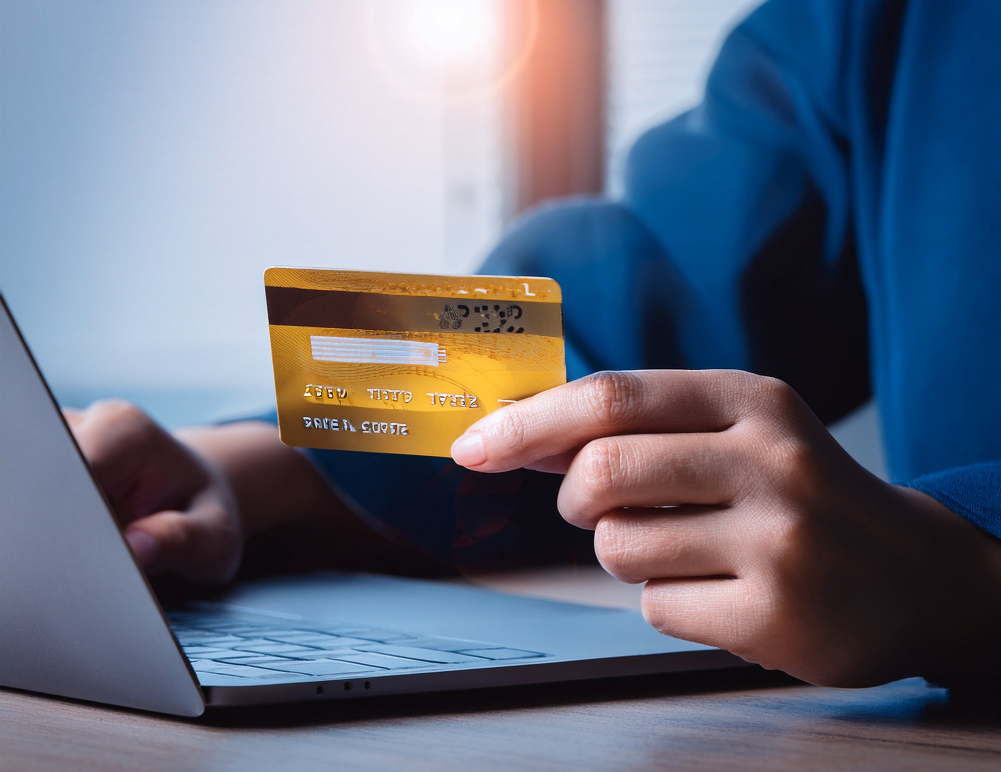 クレジットカードを持ちながらPCを操作する手元