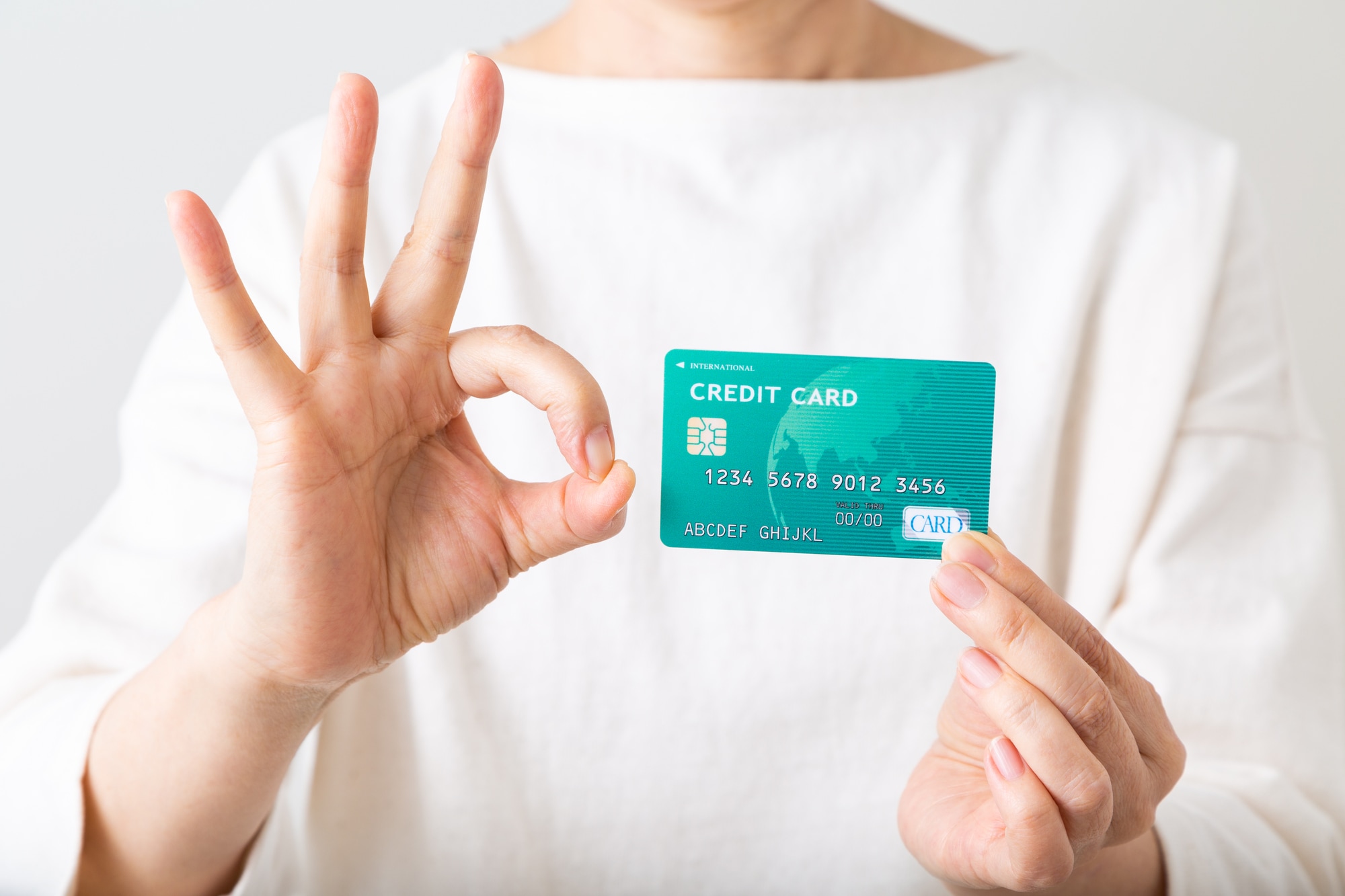 クレジットカードをもってOKサインをする女性