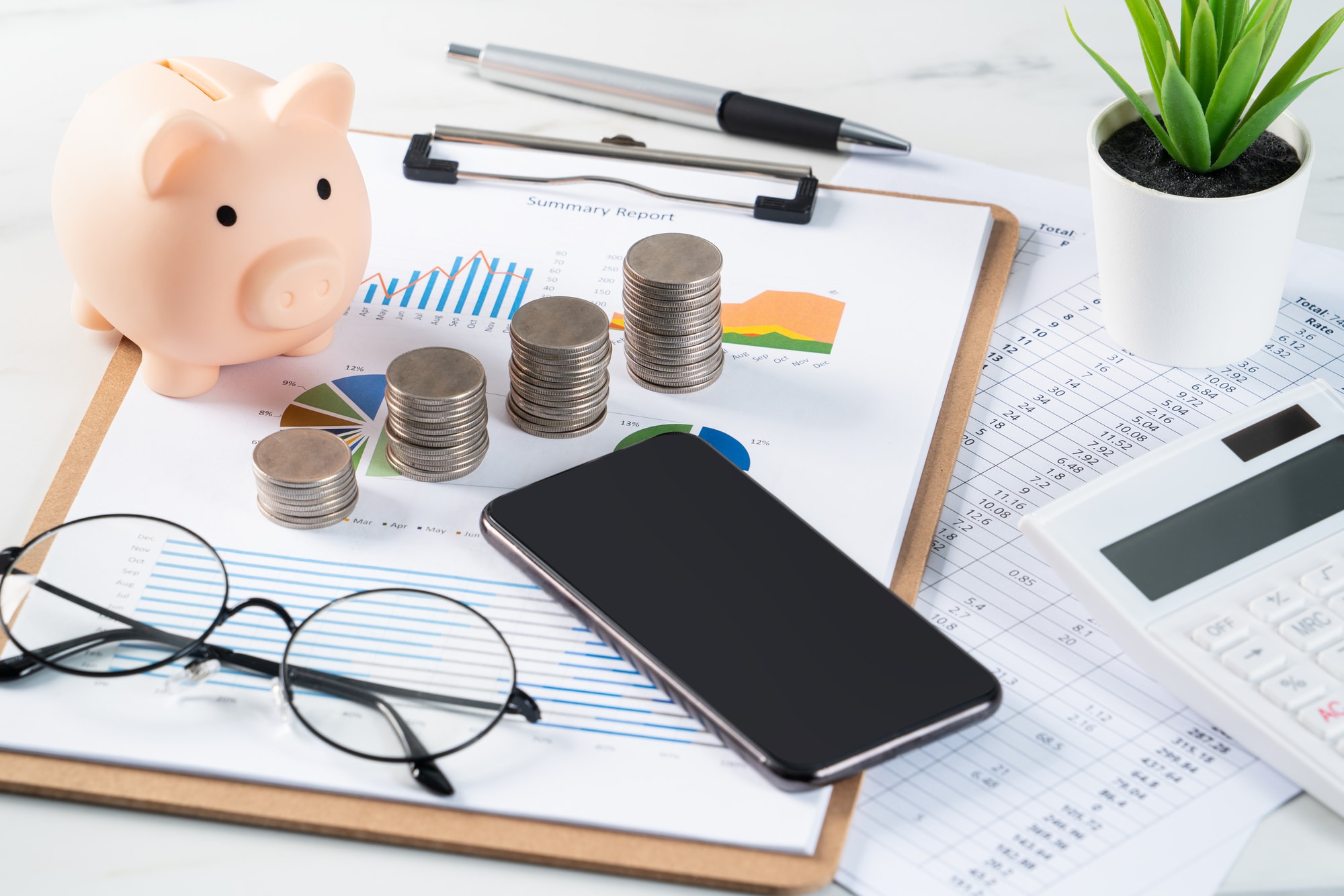 資料の上に硬貨、貯金箱、スマートフォンなどが置かれている様子