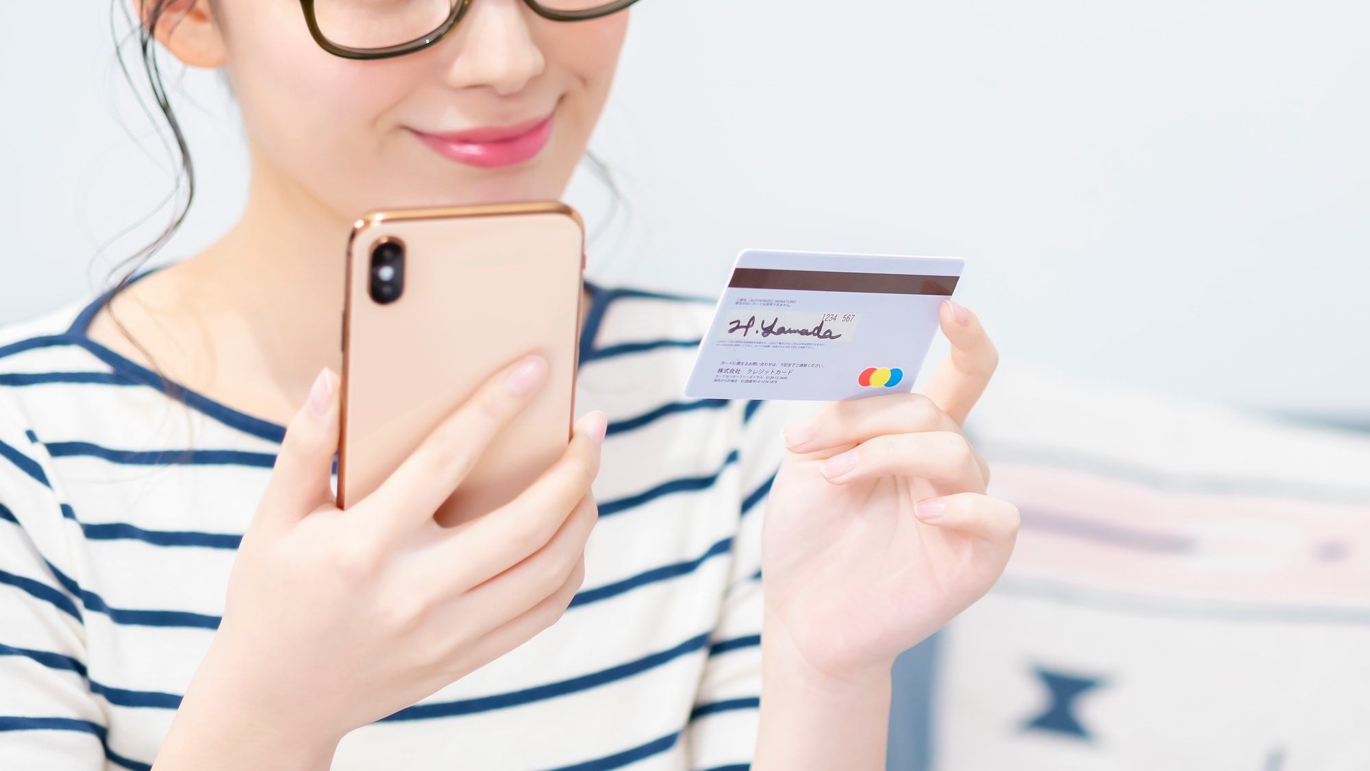 スマホとカードを持つ女性