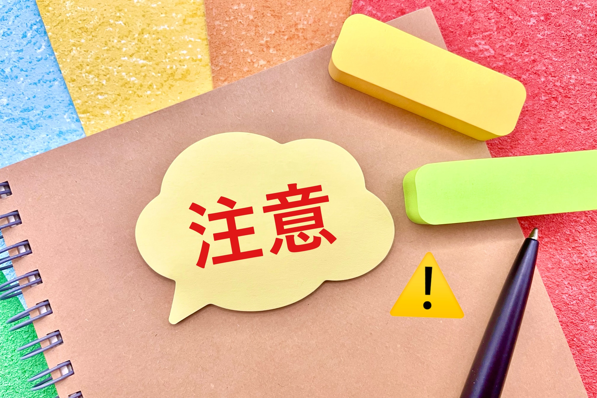 注意と書かれた吹き出しと付箋・ノート・ペン