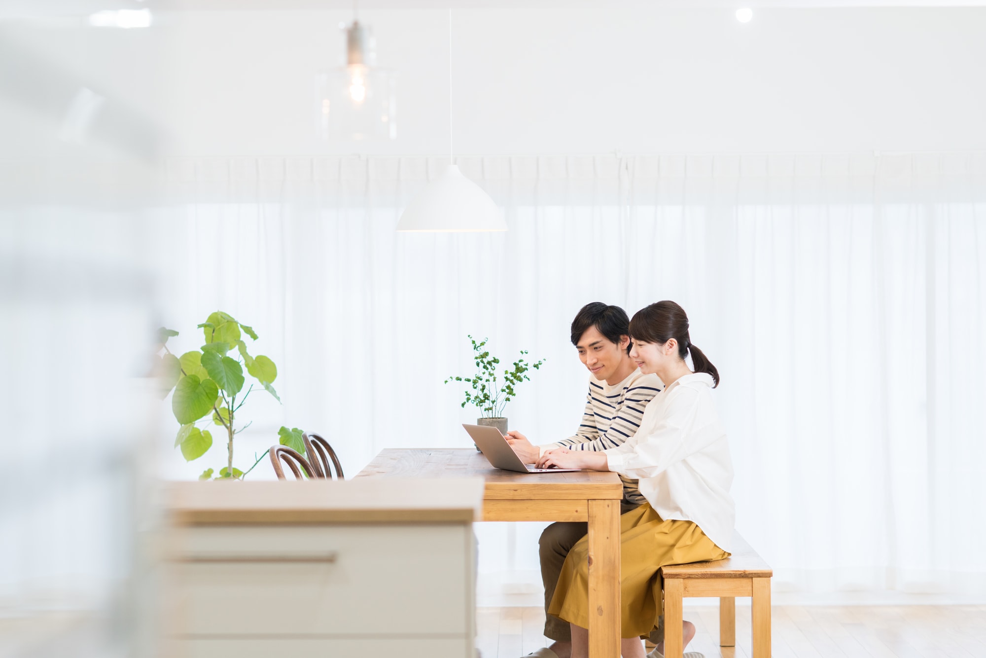 リビングでノートパソコンを見ている夫婦