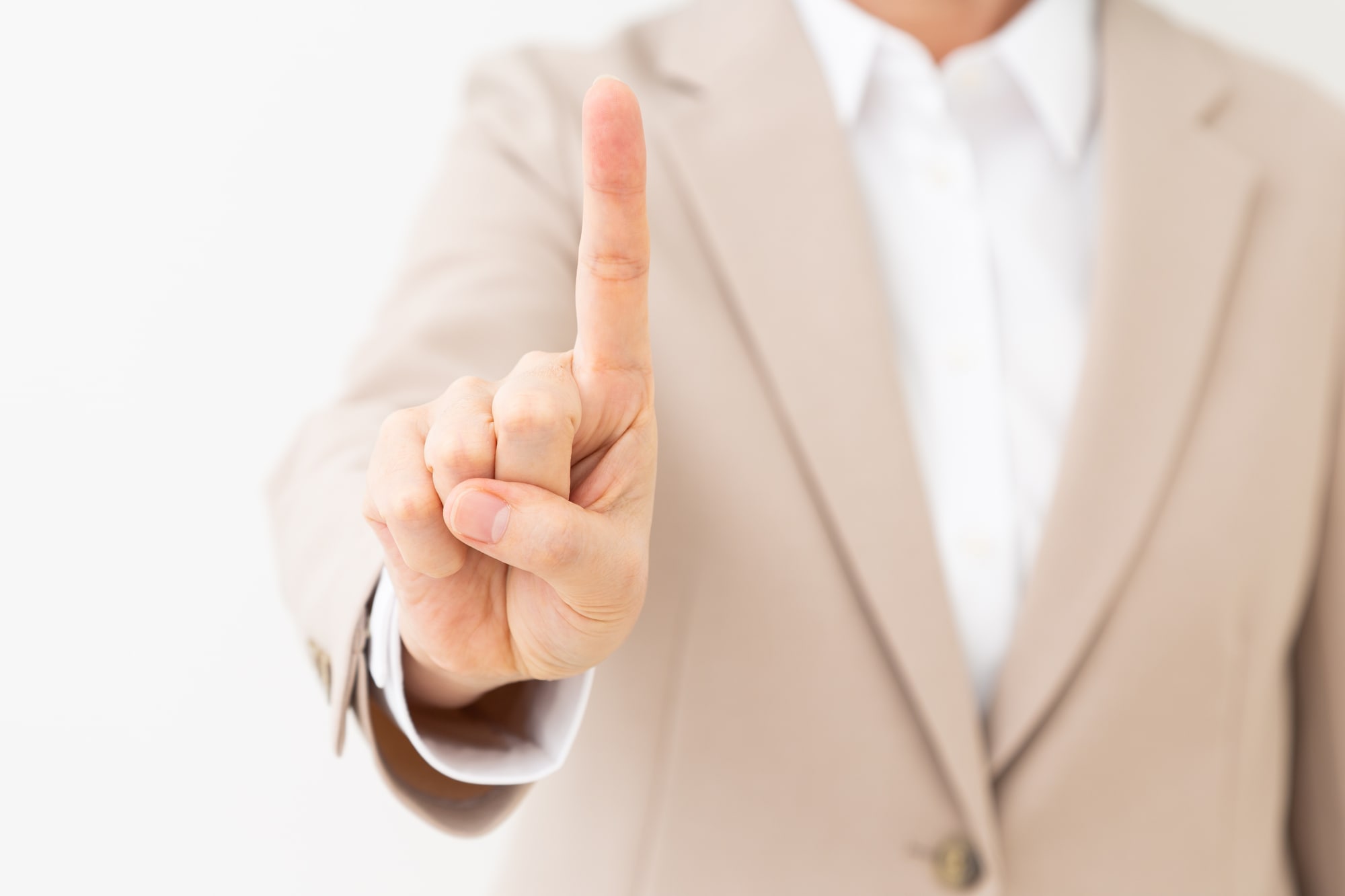 人差し指を立てるスーツ姿の人物