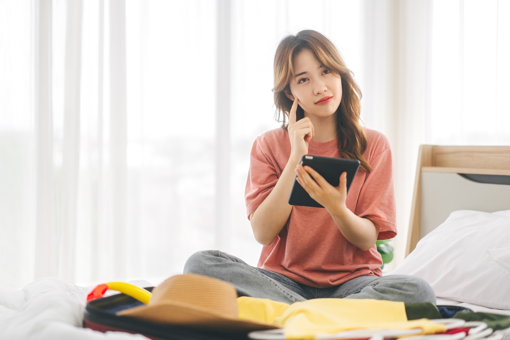 旅行の準備をしながら悩む女性