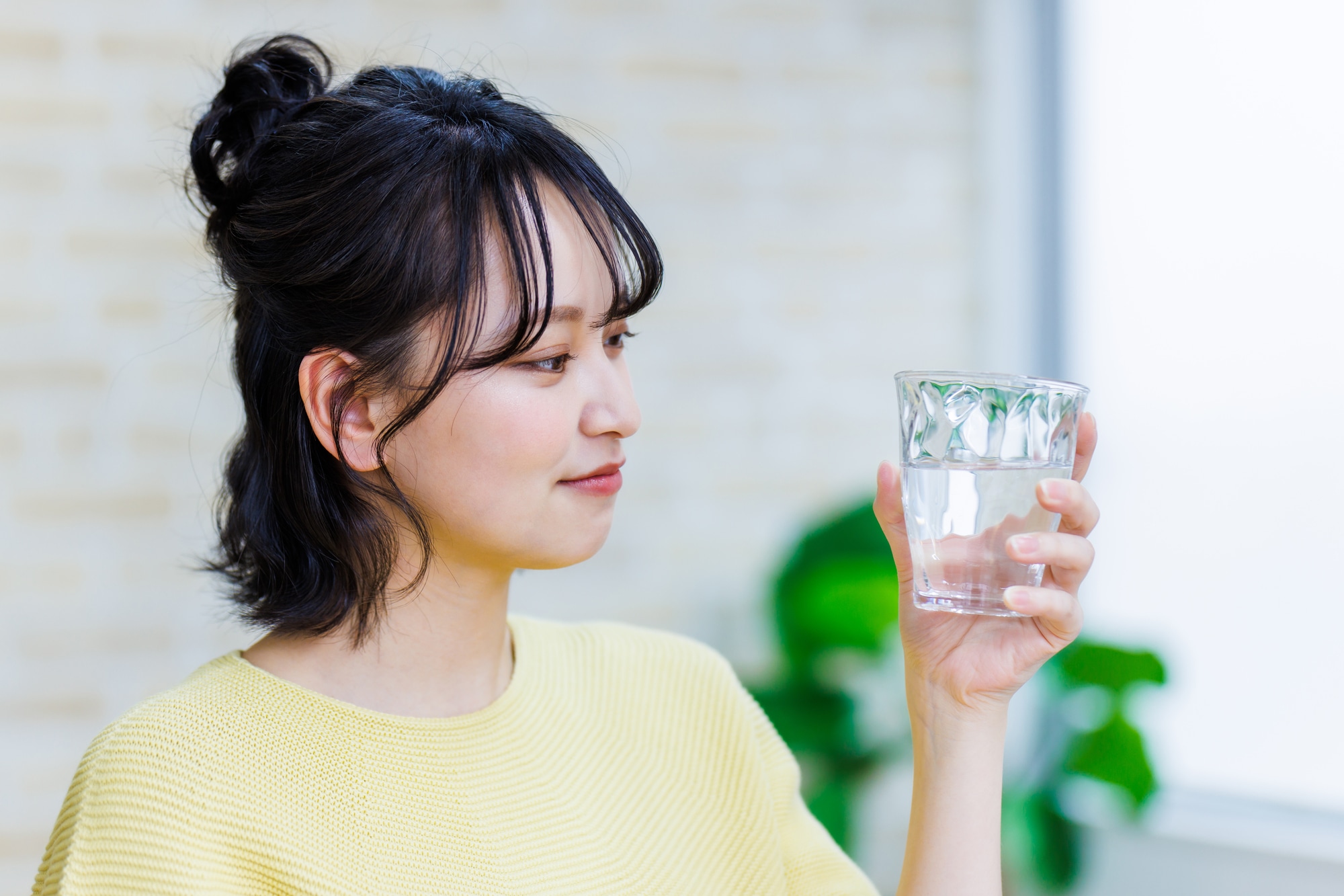 水が入ったコップを見つめる女性