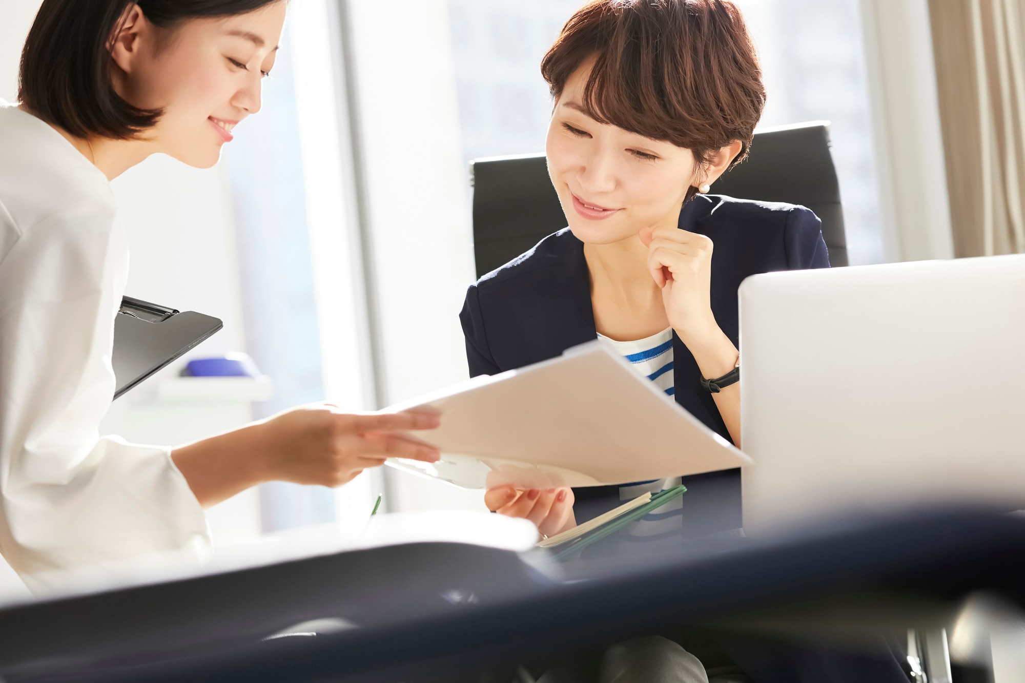 書類を見て話す2人の女性社員