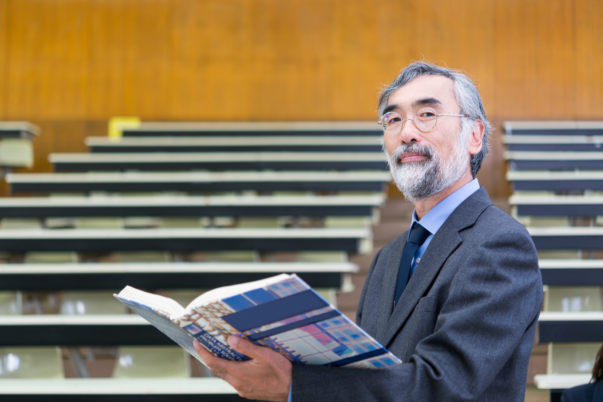 教科書を持って講義をする中高年の講師